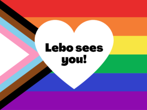 The Pride Progress flag with a white heart in the middle and black text on top that says: Lebo sees you!