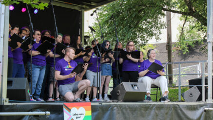 The Renaissance City Choir performing at Lebo Pride Celebration with an ally yard sign